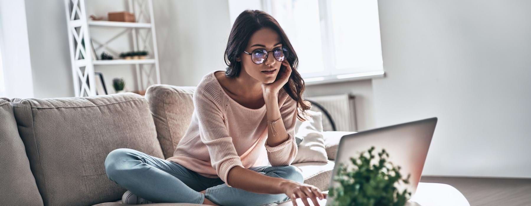 a woman sitting on a couch using a laptop